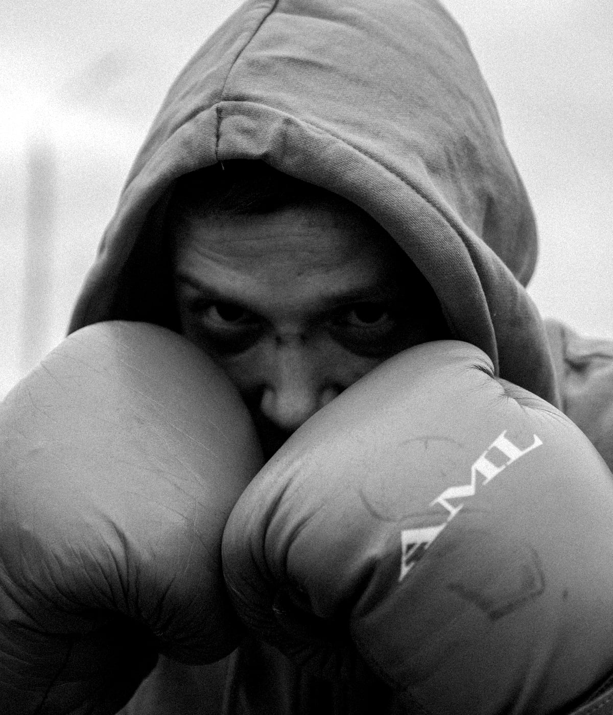 A fighter in a hood, gloves up, looking into the camera
